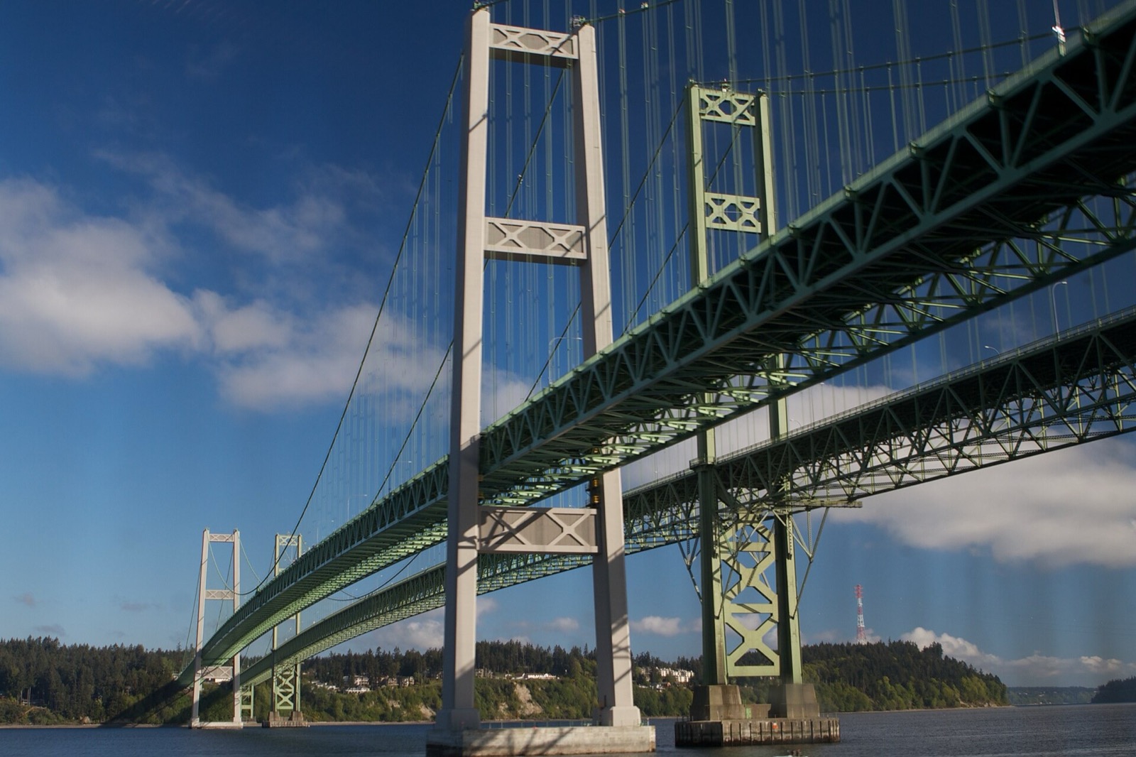 The Tacoma Narrows bridges from below, green steel against the sky